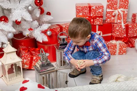 Small cute boy casual dressed standing in white room among christmas decorati Fotos Stock