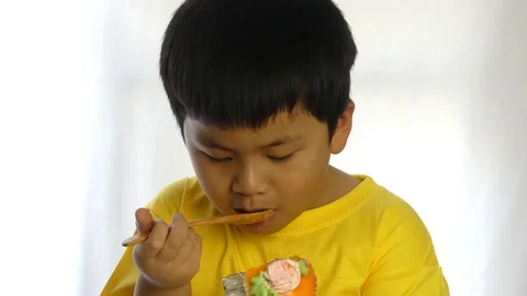 Small cute a boy eats cupcake by wooden spoon on white background, 스톡 동영상 89973687