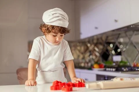 Small cute boy looking at the table with baking stuff Stock Photos