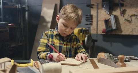 Small cute Caucasian boy working in carpentry workshop and drawing with pencil Video stock 130456081
