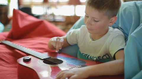 Small, cute, creative boy learning to play acoustic guitar Stock Footage 39311243