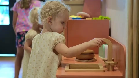 Small cute kid sisters playing on wooden toy kitchen, pretending to do housework Stock Footage 169833173