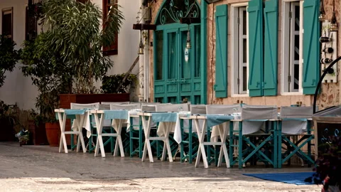 Small cute restaurant among old buildings on street. Turquoise wooden chairs and Stock Footage 235950080