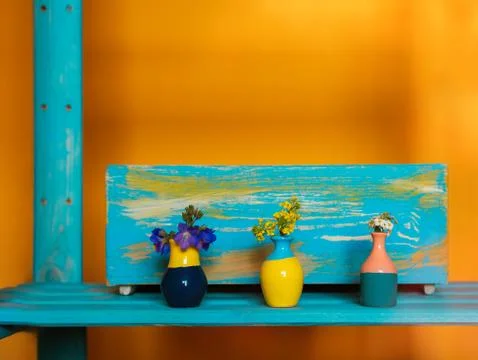 Small cute tiny vases with mini bouquet of spring flowers in front of cyan wo Stock Photos