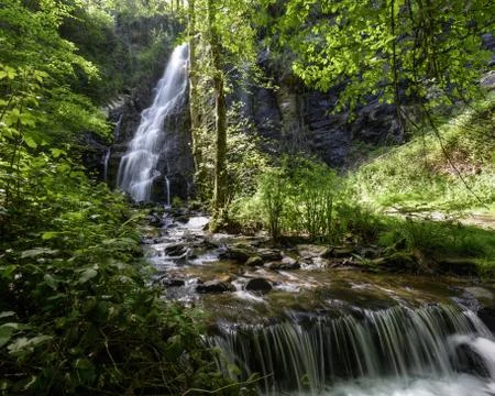 Small dam in a river downstream of a large waterfall Stock Photos
