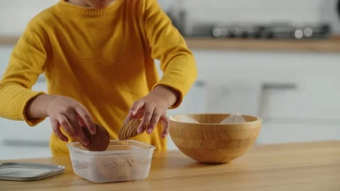 A small dark-haired boy is standing in the kitchen putting cookies into a Stock Footage 240318654