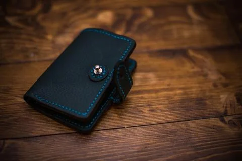 Small Dark Leather Wallet with Button Closure on Wooden Background Featurin.. Stock Photos
