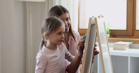Small daughter imitate mom draw picture on whiteboard using chalks Stock Footage