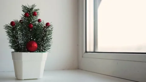 A small decorative Christmas tree stands on the windowsill Stock Footage 144597407
