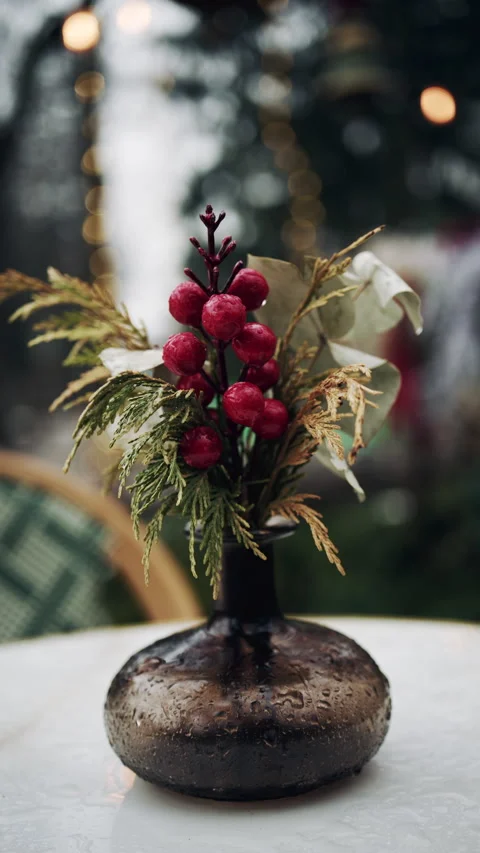 Small decorative glass vase with winter berries and greenery on outdoor table Stock Footage 331056969