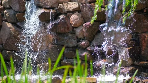 A small decorative waterfall in a park or garden. Landscape design. Stock Footage 245102125