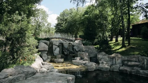 A small decorative waterfall with a stream in a park area. A cool vacation spot Stock Footage 301210126