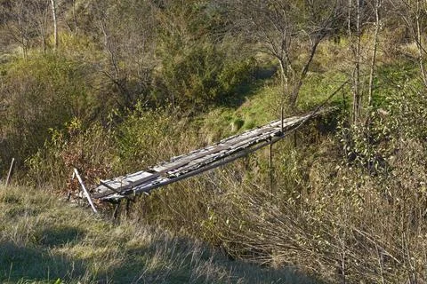 Small decrepit pedestrian bridge across narrow riverbed, Skhidnytsia, Weste.. Stock Photos