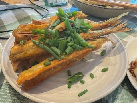 Small deep fried fish served with sprint onion slices in New Zealand Stock-Fotos