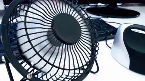 A small desk fan is positioned in front of a computer and scanner, suggesting a Stock Footage 301399043