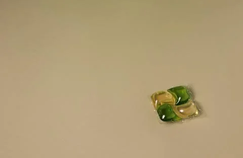 Small detergent pods placed on a plain surface during a laundry preparation 스톡 사진
