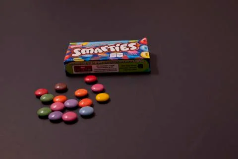 Small different coloured Smarties next to box Stock-Fotos