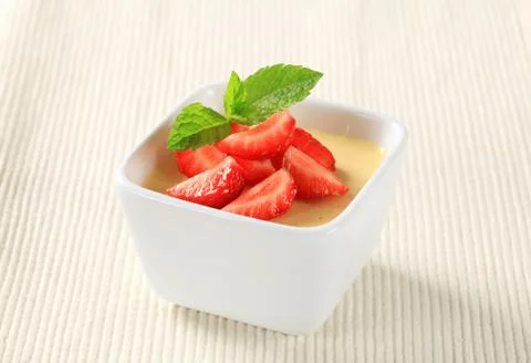 Small dish of vanilla pudding topped with strawberries Stock Photos