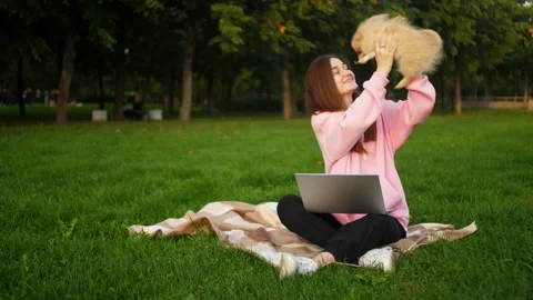 A small dog interferes with a girl in the park with a laptop to study or work Stock Footage 171756653