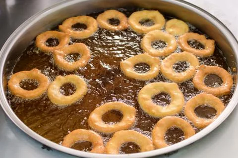 Small donuts being deep fried in boiling oil in a large pan, at a food market Foto stock