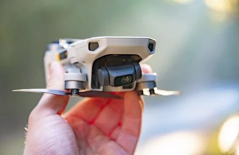 Small drone holded in hand against blurry background. Drone regulations concept Stock Photos