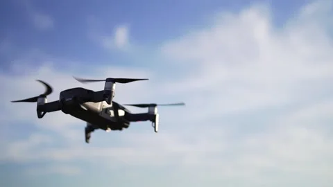 A small drone hovered above the ground against a beautiful sky with clouds Video stock 139890686
