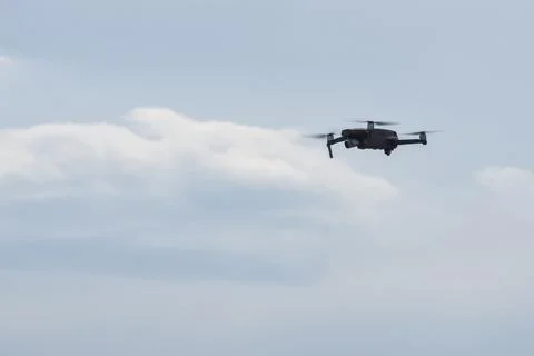 Small drone quadcopter flies with a camera on a background of blue sky with c Stock Photos