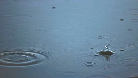 Small drops of rain falling on a puddle Stock Footage 131382793