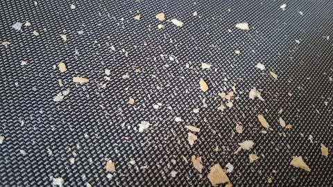 Small dry bread crumbs scattered on a dark textured surface Stock Photos