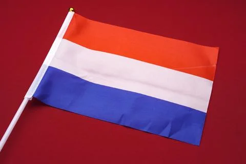 Small Dutch flag isolated on a red background. Stock Photos