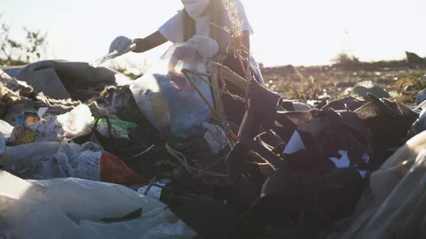 Small eco volunteer in gloves cleaning lawn of trash at countryside. Waste Stock-Footage 307828237