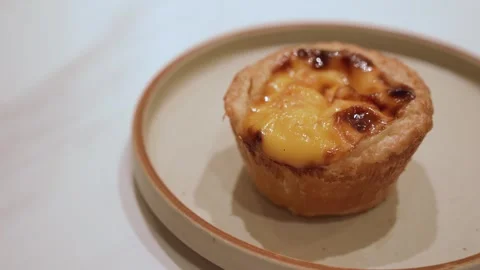 A small egg tart pastry served on a neutral plate Stock Footage 326019764