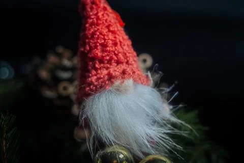 A small elf with a red knitted hat and white beard sits among. Stock Photos