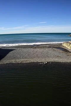 Small empty beach between walls on a sunny day Stock Photos