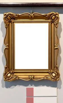 Small empty blank gold decorative vertical painting frame on a museum wall,.. Foto stock