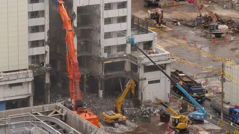 Small excavator sort debris falling down from breaking building Stock Footage 130285799