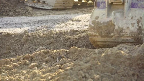 A small excavator uses its bucket to spread fill dirt around Stock Footage
