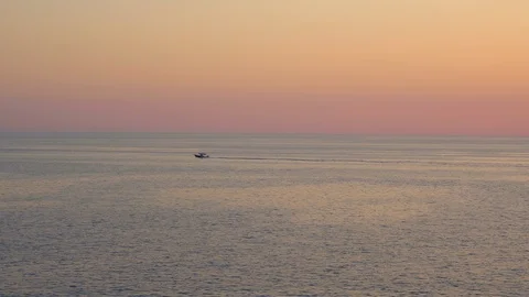 Small fast boat is moving in open sea during warm purple sunset Stock Footage 114917216