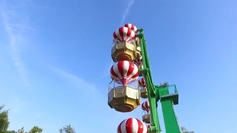 Small Ferris wheel with hot-air balloon themed compartments on a sunny day Stock Footage 71960216