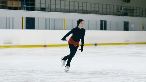 Small figure skater making toe loop inside ice arena Stock Footage 101630647