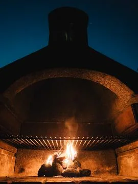 Small fire burning inside a barbecue grill at night, with the smoke coming out Stock Photos