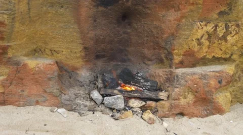 Small fire on the sand near the wall of yellow shell rock. Picnic on beach. Video stock 65189387