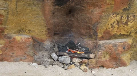 Small fire on the sand near the wall of yellow shell rock. Picnic on beach. Stock Footage 65193134