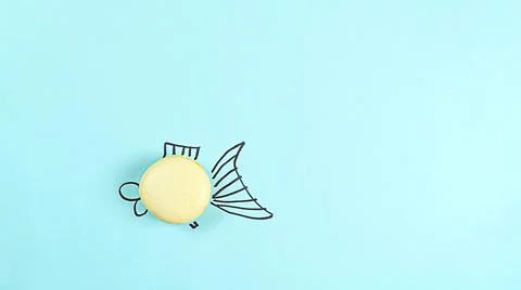 Small fish macaroon cake on a blue background concept with copy space Foto stock