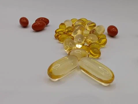 A small fish on a white background consists of omega 3 capsules and vitamins in  Stock Photos