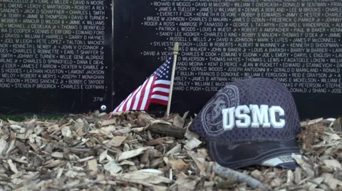 Small flag and U.S. Marine Corps (USMC) hat next to Vietnam Wall That Heals Stock Footage 47389860