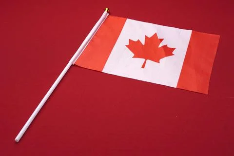 Small flag of Canada isolated red background. Stock Photos