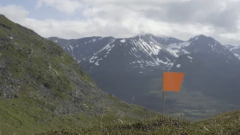 Small flag planted in the grass with the mountains behind, Tromso, Norway Stock Footage 102154629