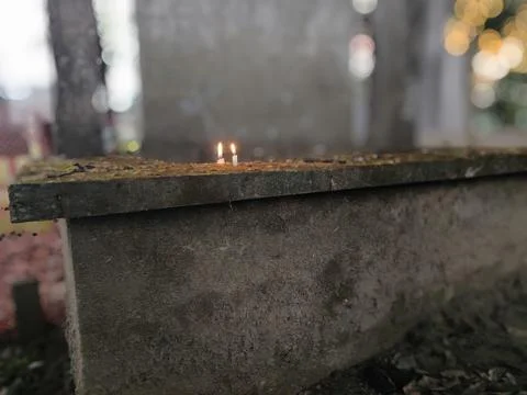 A small flame burns atop a moss-covered concrete structure with a rectangul.. Stock Photos