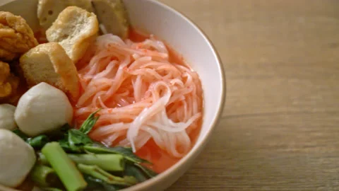 Small flat rice noodles with fish balls and shrimp balls in pink soup, Yen Stock Footage 154987110